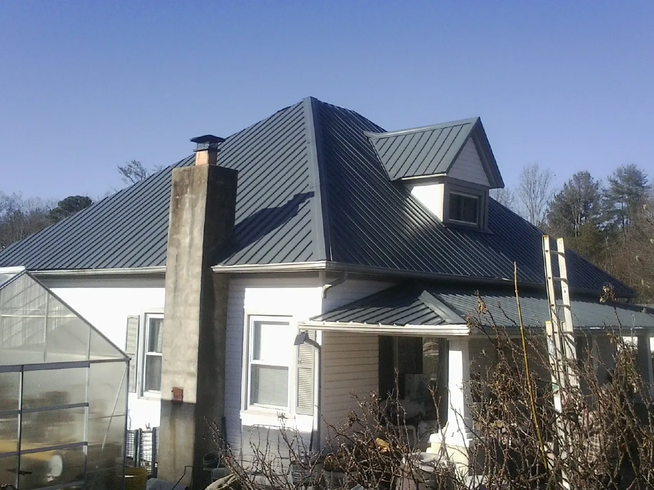 Dark blue standing seam metal roof on a white farmhouse with dormer — Slate & Tile Roof Repair by Roofing Brothers in North Waterboro