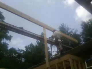 Carpenter setting a ridge beam over a new addition frame — Ice Dam Removal by Roofing Brothers in North Waterboro