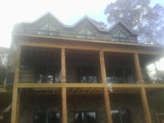 Dormers and porch framing on a large log home under construction — Roof Coating work by our crew in North Waterboro