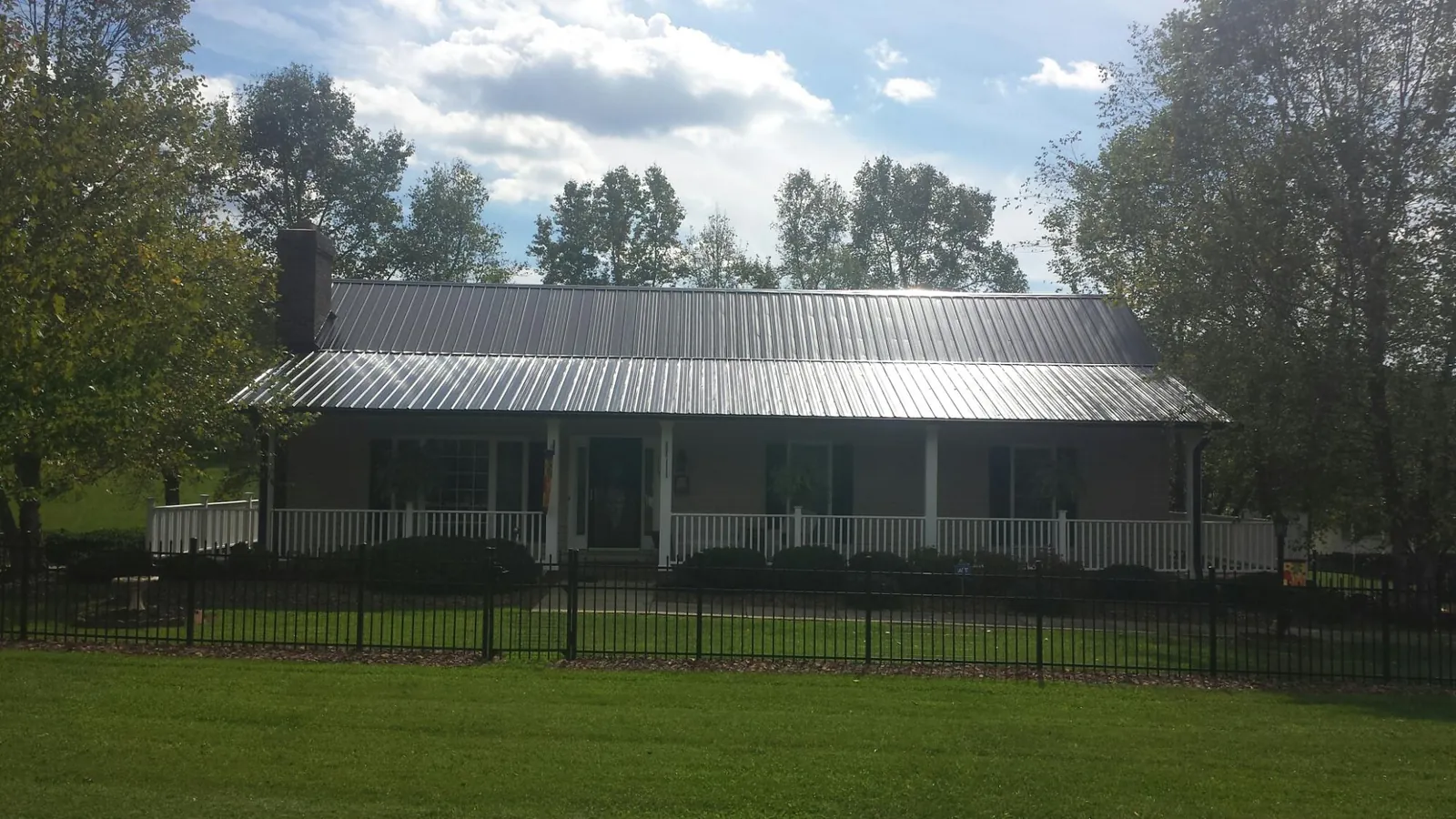 Gray metal roof on a brick ranch with a full width front porch — Gutter Guard Installation work by our crew in North Waterboro