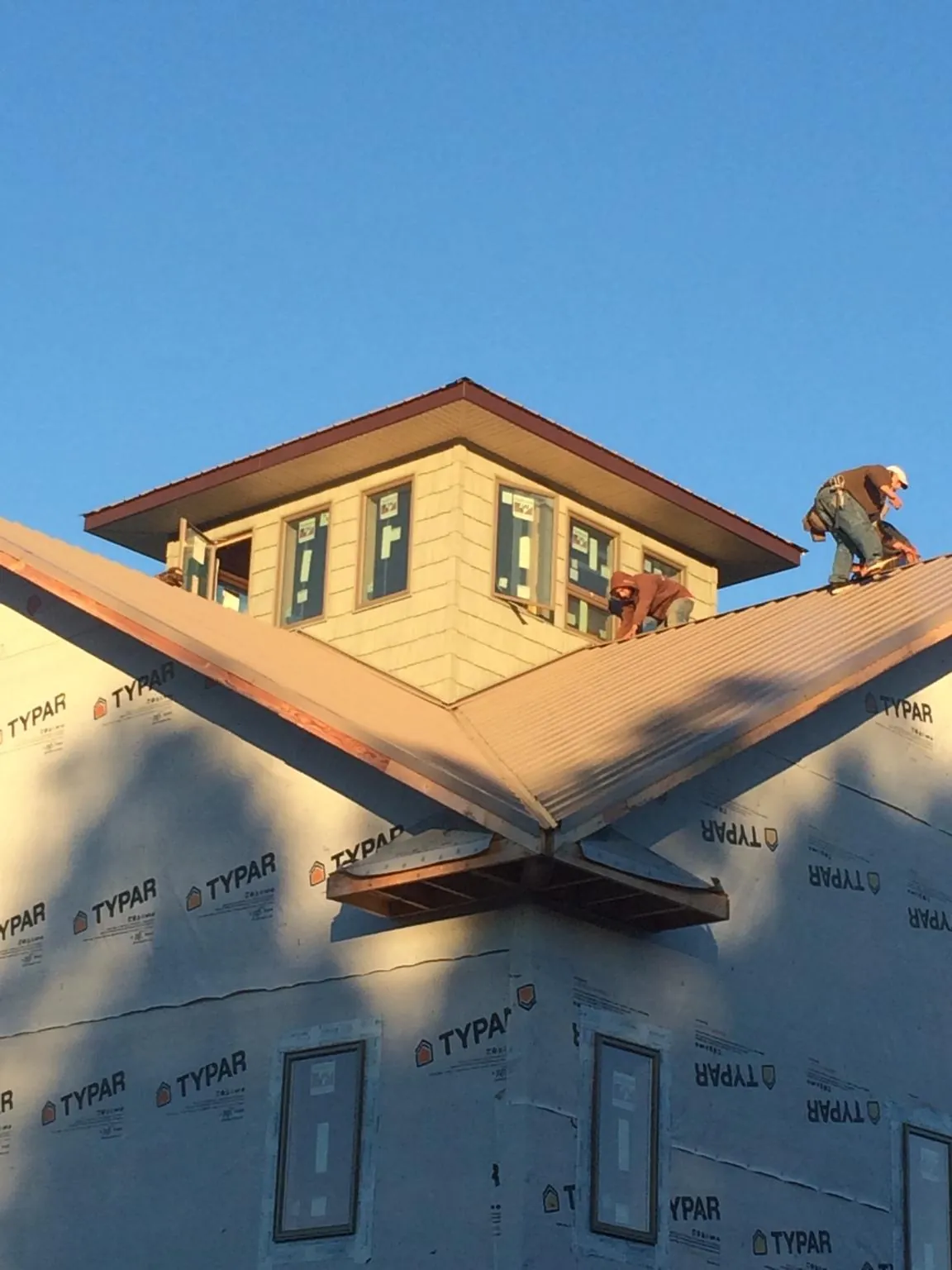 Roofers working around a rooftop cupola on a new metal roof at sunset — Roof Waterproofing in North Waterboro by Roofing Brothers